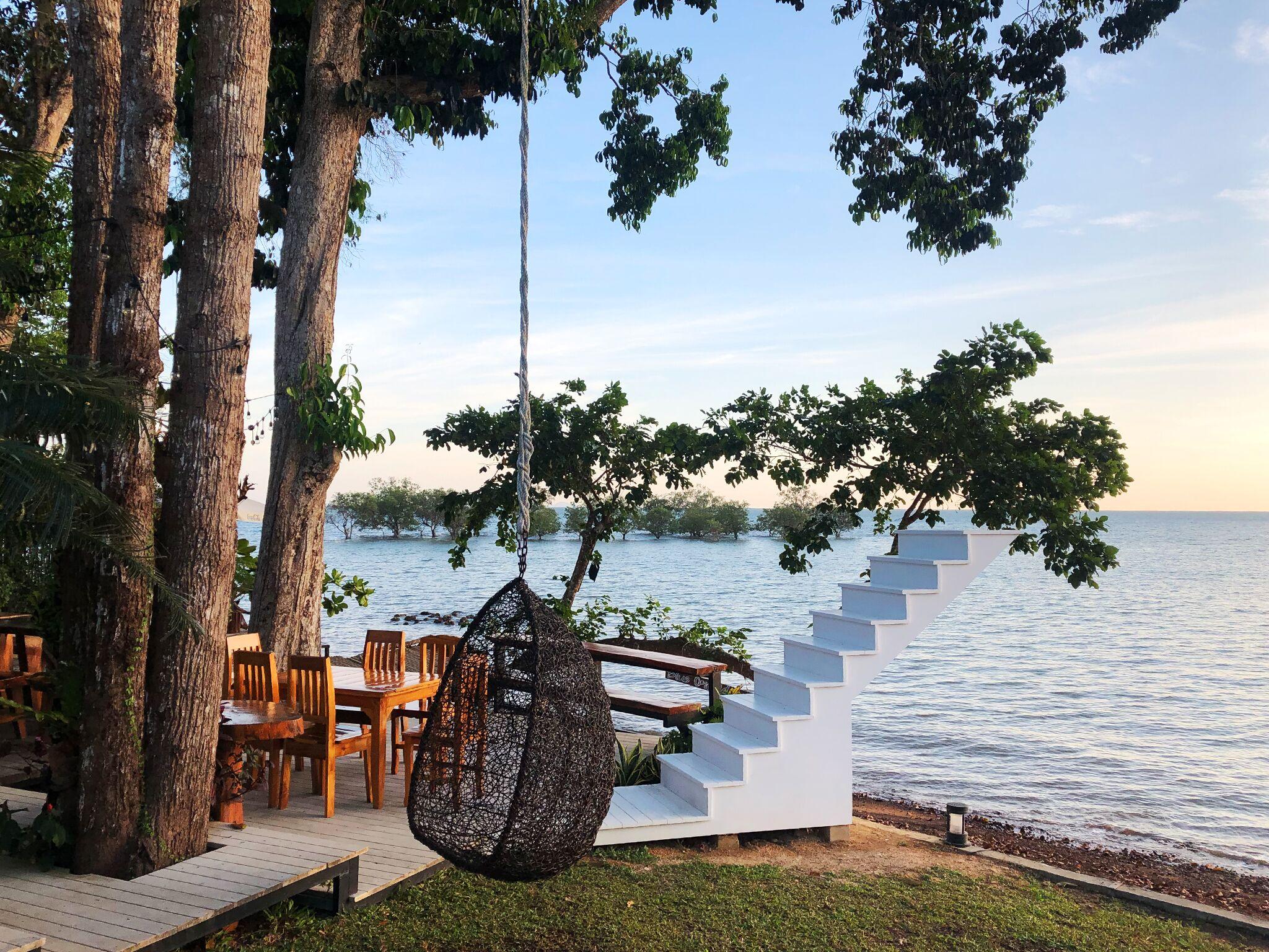 Signature sunset deck with a hanging chair and white steps to the sand