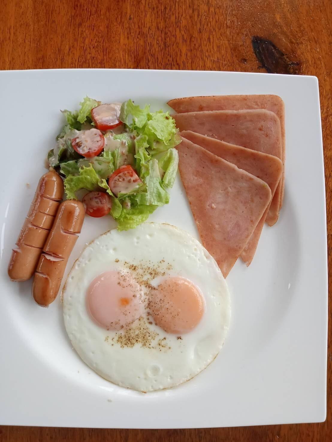 Breakfast plate with fried eggs, ham, sausage and salad