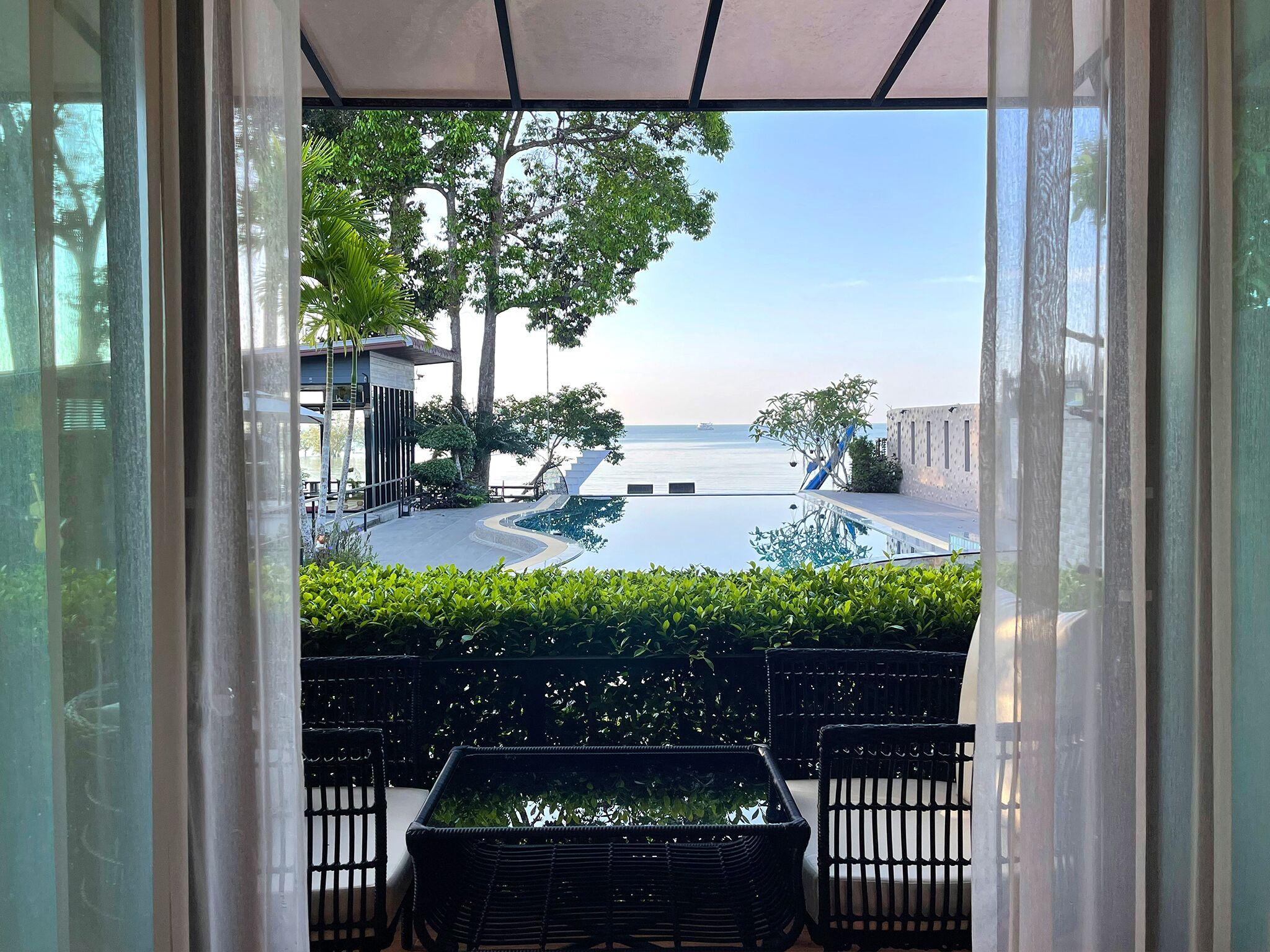 Room opening through sheer curtains to the infinity pool and sea